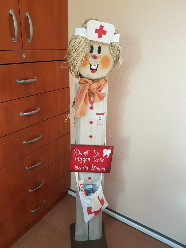 Holzfigur mit Schwesternhaube und einem Schild